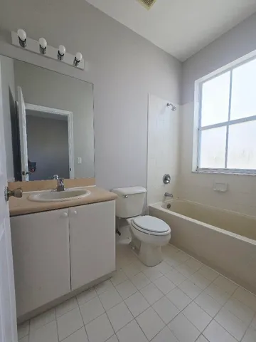a bathroom with a toilet a sink a mirror a bathtub and window