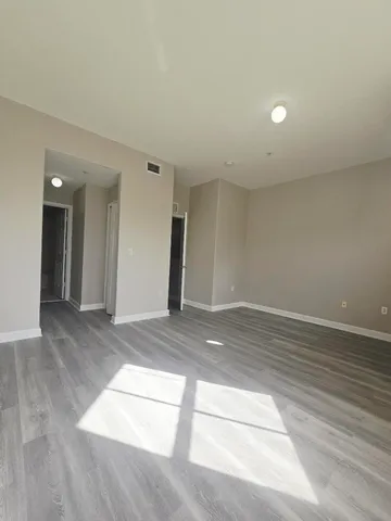 an empty room with wooden floor and windows