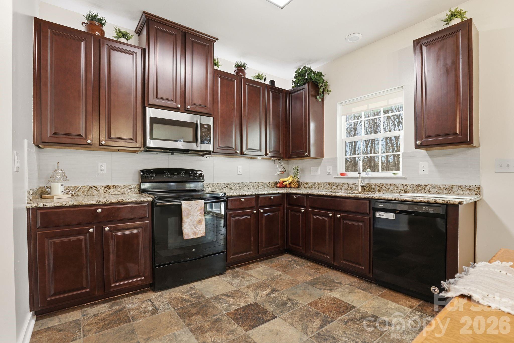 7532 West Berkeley Road, Unit 25 Denver, NC 28037 - Photo 9 of 36 a kitchen with granite countertop wooden cabinets a stove top oven and granite counter top