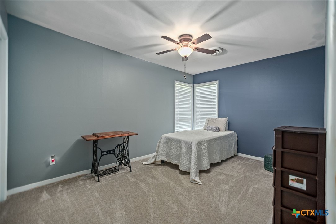 519 Travis Street Port Lavaca, TX 77979 - Photo 13 of 26 a spacious bedroom with a bed and a chandelier