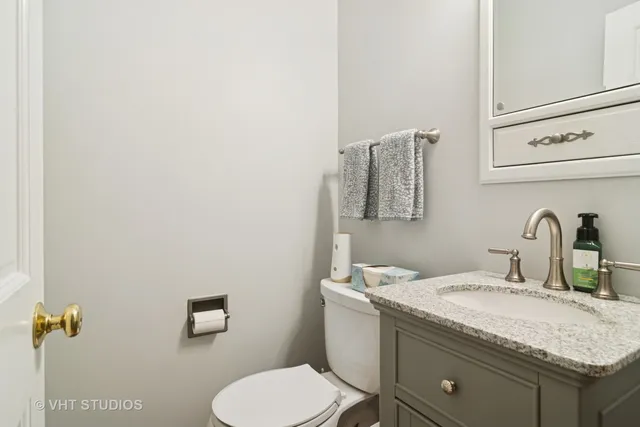 a bathroom with a granite countertop sink and a toilet