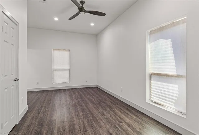 an empty room with wooden floor cabinet and windows