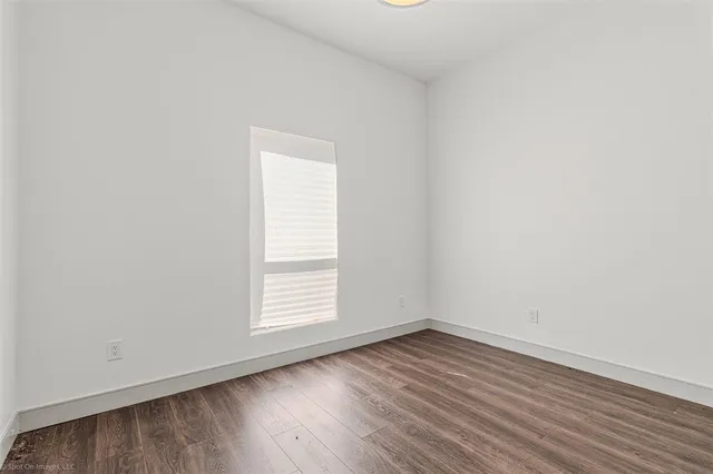 an empty room with wooden floor and window