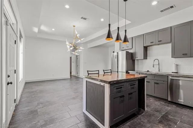 a kitchen with kitchen island stainless steel appliances a sink stove and refrigerator