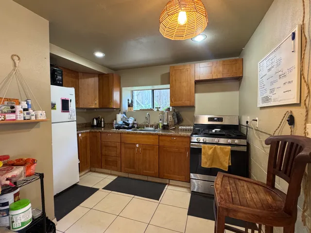 a kitchen with stainless steel appliances granite countertop a stove top oven a sink a dining table and chairs with wooden floor