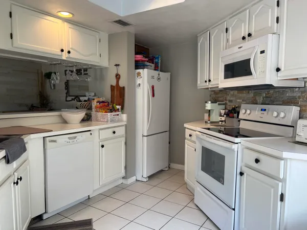 a kitchen with white cabinets and white appliances