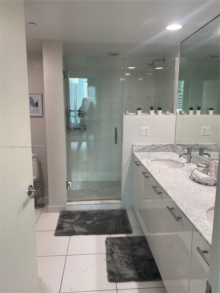 55 Southeast 6th Street, Unit 1903 Miami, FL 33131 - Photo 13 of 23 a bathroom with a sink a toilet a mirror and shower