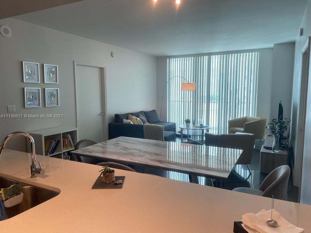 55 Southeast 6th Street, Unit 1903 Miami, FL 33131 - Photo 10 of 23 a kitchen with a table chairs and a refrigerator