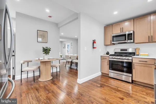 a kitchen with stainless steel appliances a stove a microwave a sink a refrigerator white cabinets and wooden floor