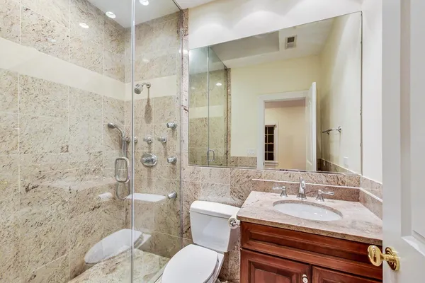 a bathroom with a granite countertop sink toilet and shower