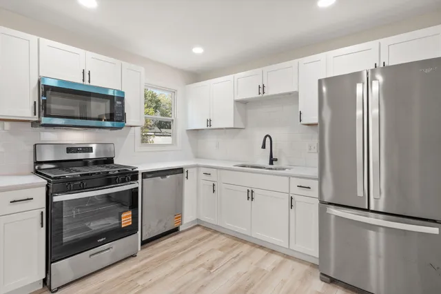 a kitchen with cabinets stainless steel appliances a sink and wooden floor