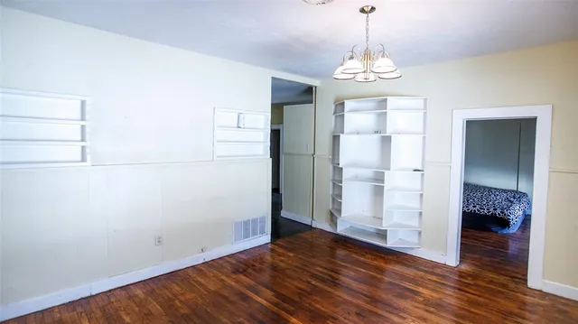 a view of a hallway with wooden floor and a chandelier