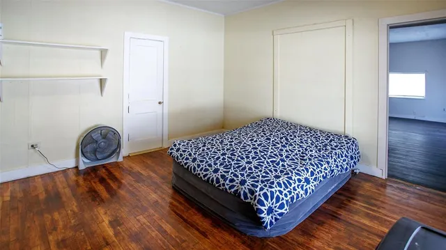 a bedroom with a bed and hardwood floor