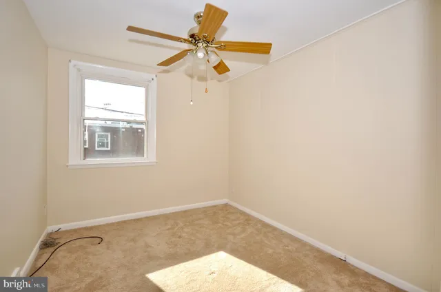 an empty room with a window and a fan