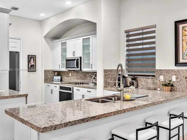 a kitchen with granite countertop a sink stainless steel appliances and white cabinets