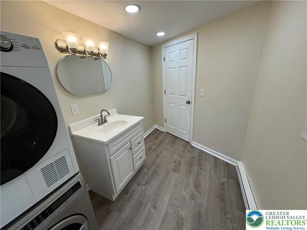 a view of a hallway with wooden floor and a bathroom