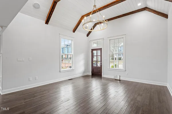a view of an empty room with wooden floor and windows