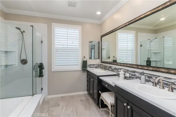 a bathroom with a double vanity sink a large mirror and a bathtub