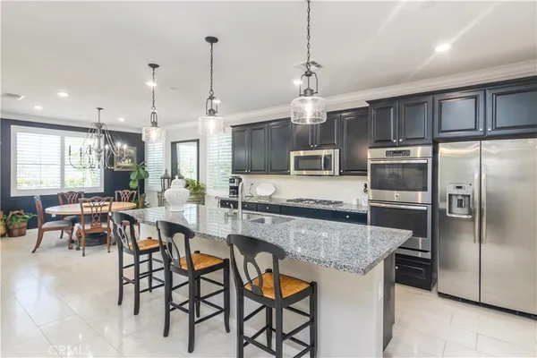 a kitchen with stainless steel appliances granite countertop a sink a stove a refrigerator cabinets and chairs