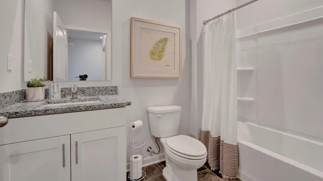 a bathroom with a granite countertop sink mirror vanity and toilet