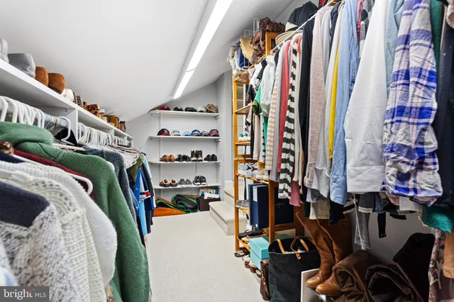 a view of walk in closet with clothes and shoes