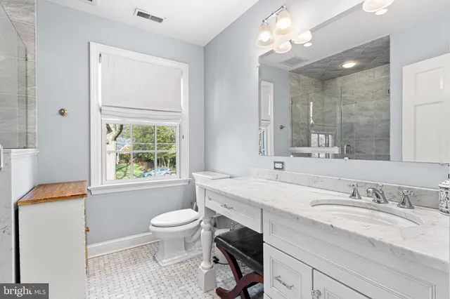 a bathroom with a granite countertop sink toilet a large mirror and a window