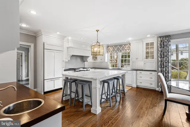 a kitchen with stainless steel appliances granite countertop a stove a refrigerator a kitchen island a stove and a wooden floors