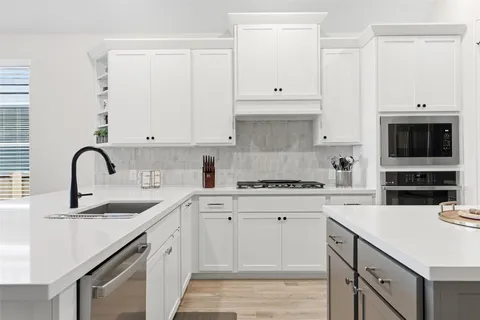 a kitchen with cabinets appliances a sink and a counter space