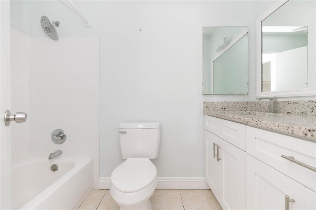 7531 Abonado Road, Unit 1 Tampa, FL 33615 - Photo 15 of 26 a bathroom with a granite countertop toilet a sink and a bathtub