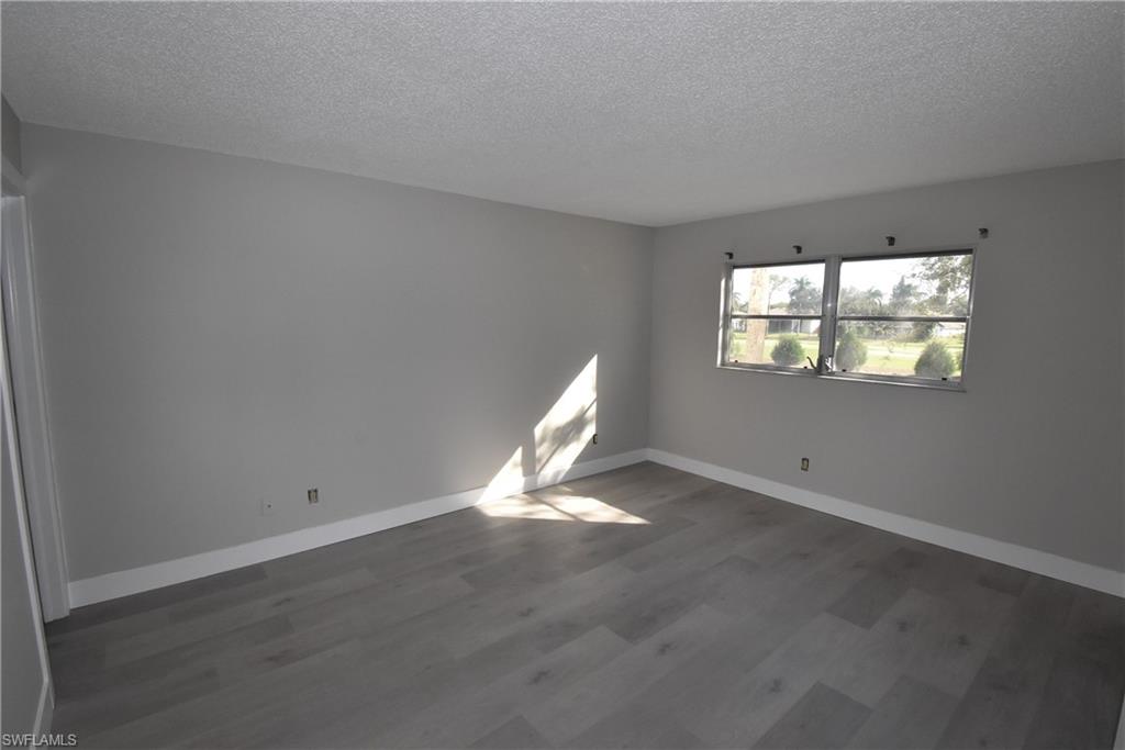5667 Rattlesnake Hammock Road, Unit B205 Naples, FL 34113 - Photo 15 of 16 Empty room featuring a textured ceiling and dark wood-style flooring