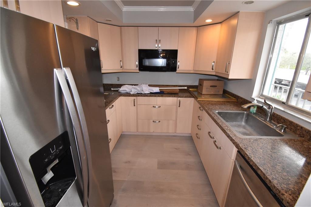 5667 Rattlesnake Hammock Road, Unit B205 Naples, FL 34113 - Photo 5 of 16 Kitchen featuring stainless steel appliances, ornamental molding, recessed lighting, dark stone counters, and light wood-style flooring