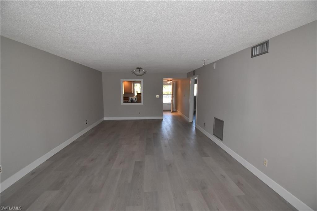 5667 Rattlesnake Hammock Road, Unit B205 Naples, FL 34113 - Photo 6 of 16 Empty room featuring a textured ceiling and light wood-style floors