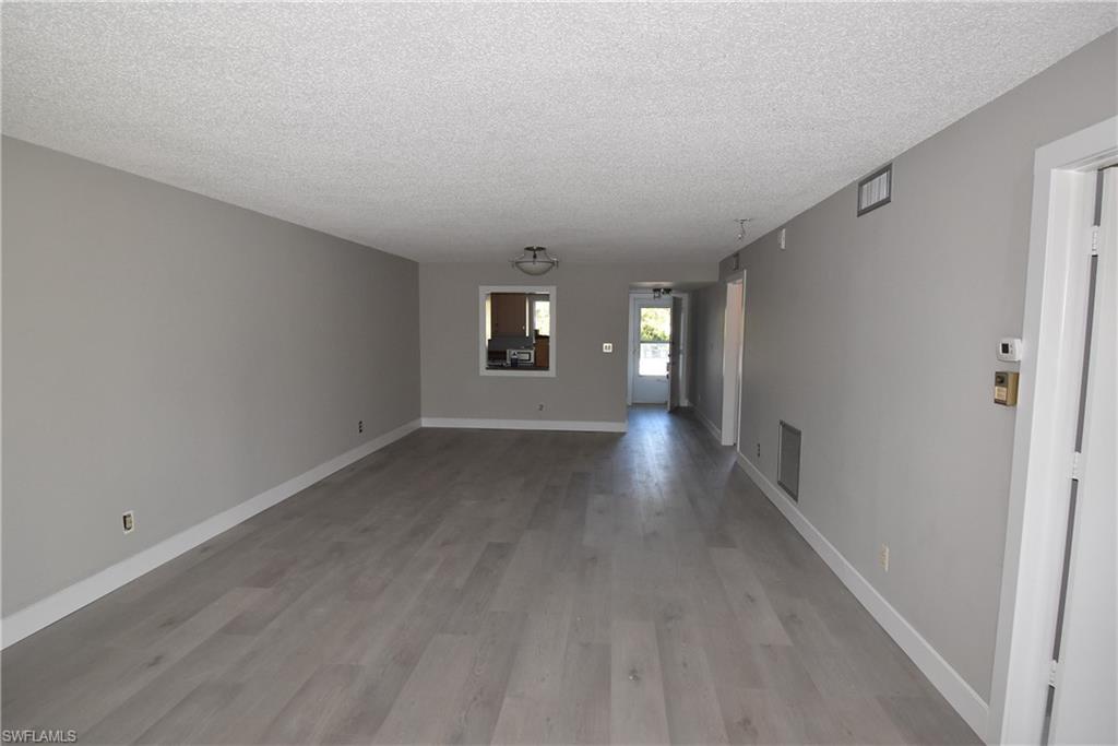 5667 Rattlesnake Hammock Road, Unit B205 Naples, FL 34113 - Photo 7 of 16 Unfurnished room featuring light wood-type flooring and a textured ceiling
