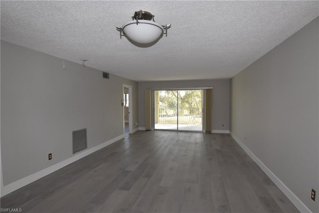 5667 Rattlesnake Hammock Road, Unit B205 Naples, FL 34113 - Photo 8 of 16 Empty room with a textured ceiling and wood finished floors