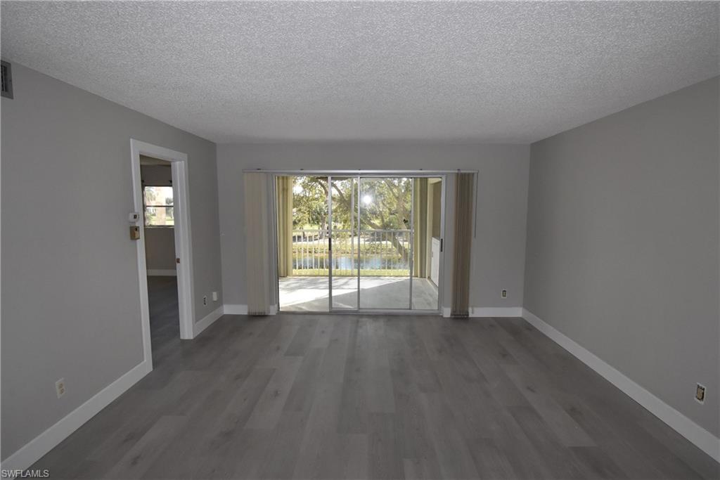 5667 Rattlesnake Hammock Road, Unit B205 Naples, FL 34113 - Photo 9 of 16 Empty room with a textured ceiling, dark wood-style flooring, and a water view