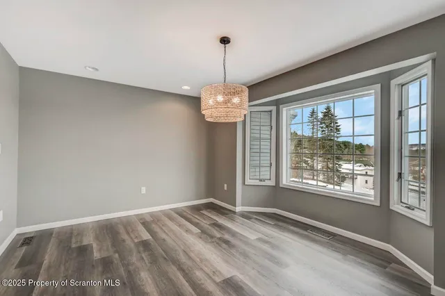 a kitchen with stainless steel appliances a refrigerator a sink dishwasher a oven a dining table and chairs with wooden floor