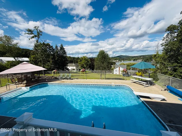 a view of a swimming pool with lawn chairs under an umbrella