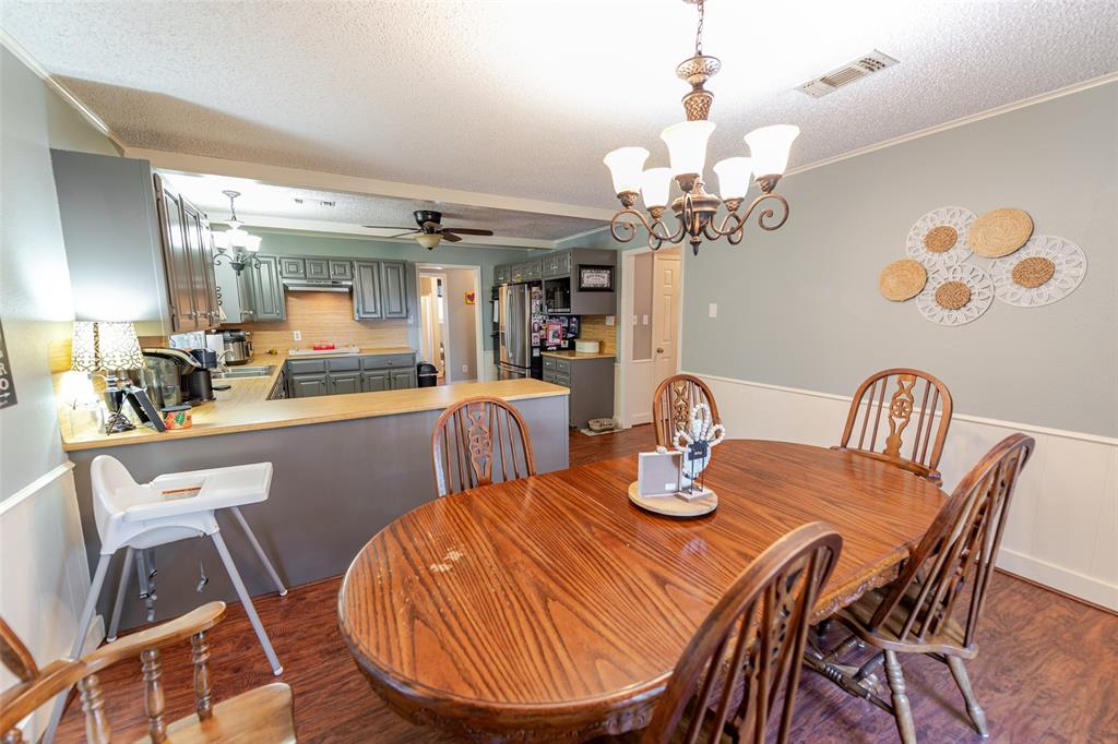 180 Se Creek Scroggins, TX 75480 - Photo 8 of 24 a dining room with wooden floor a chandelier a wooden table and chairs