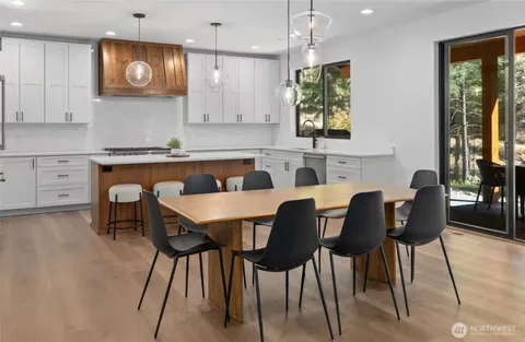 a kitchen with stainless steel appliances granite countertop a stove a sink a microwave a dining table and chairs with wooden floor