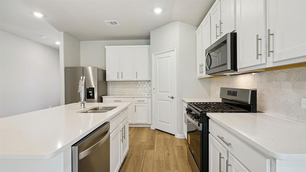 2218 Rannoch Street Sherman, TX 75092 - Photo 4 of 28 a kitchen with stainless steel appliances a sink stove refrigerator and cabinets