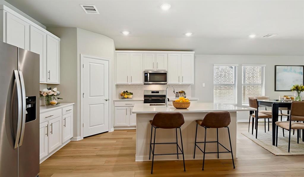 2218 Rannoch Street Sherman, TX 75092 - Photo 8 of 28 a kitchen with stainless steel appliances a stove a refrigerator a white table and chairs