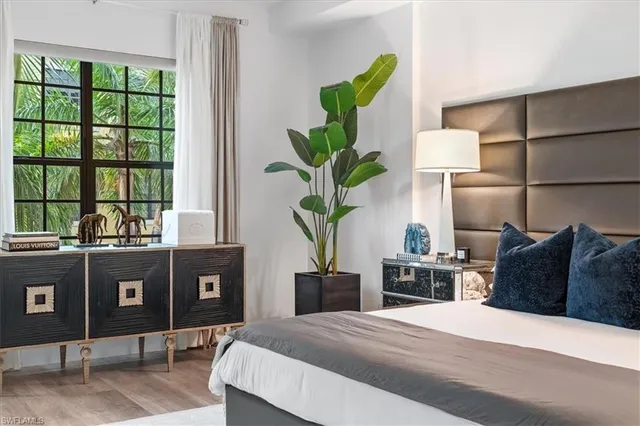 a bedroom with a bed table flowerpot and window