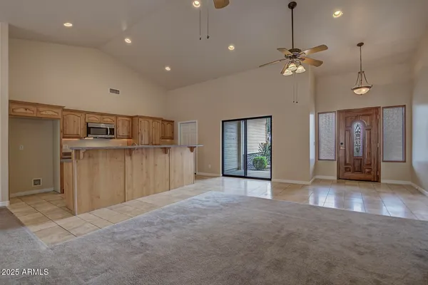 an empty room with kitchen view and wooden floor