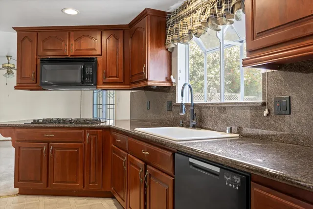 a kitchen with granite countertop a sink stainless steel appliances and cabinets