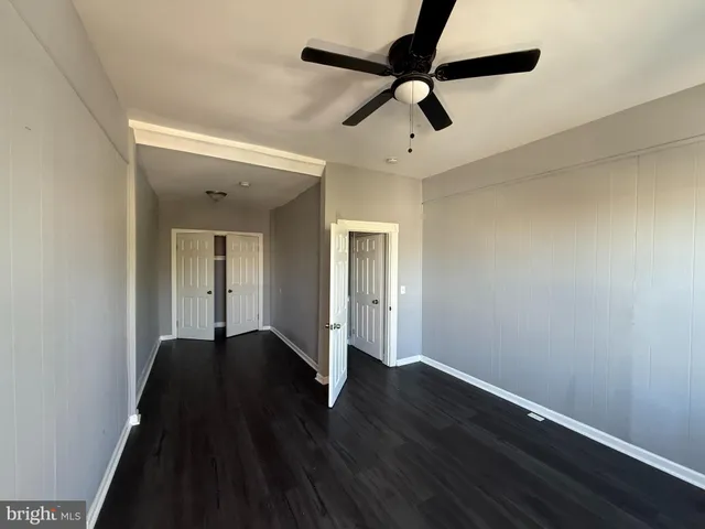 a view of empty room with wooden floor and fan