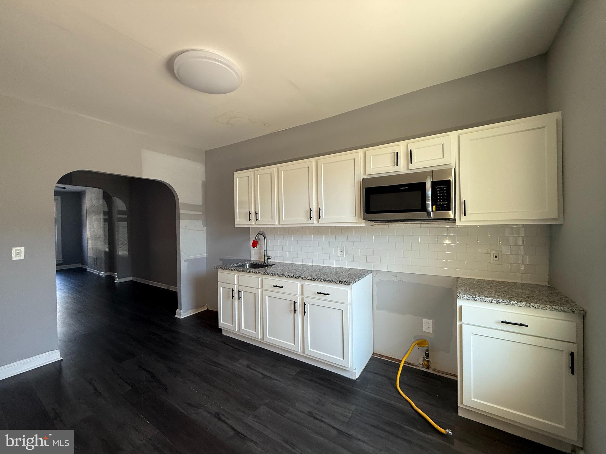 1635 Normal Avenue Baltimore, MD 21213 - Photo 6 of 18 a kitchen with stainless steel appliances a microwave a stove and white cabinets
