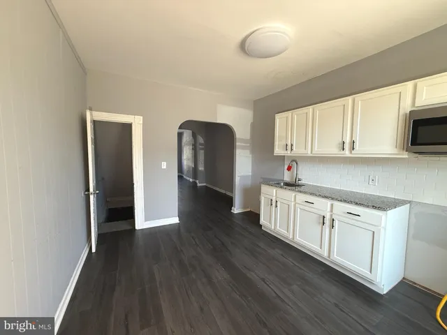 a kitchen with stainless steel appliances granite countertop a stove a sink and white cabinets with wooden floor