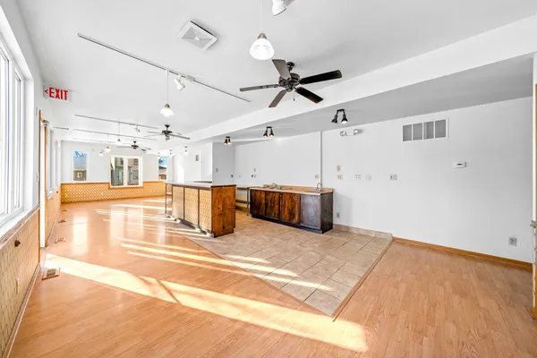a large white kitchen with kitchen island a stove a sink dishwasher and a refrigerator with wooden floor