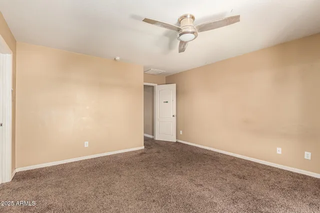 an empty room with a ceiling fan and a window