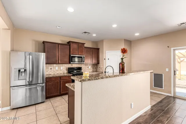 a kitchen with stainless steel appliances granite countertop a refrigerator sink stove microwave and cabinets